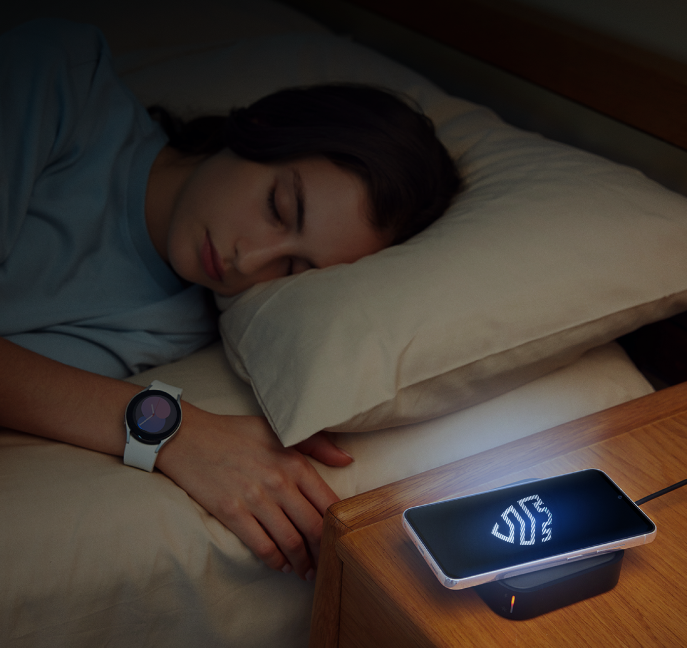 Pessoa dormindo no escuro ao lado de um dispositivo móvel Samsung exibindo um logotipo Knox iluminado.